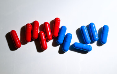 Red and Blue Pill Capsules on White Background with Strong Shadows © Anna Hoychuk