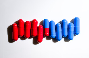 Red and Blue Pill Capsules on White Background with Strong Shadows © Anna Hoychuk