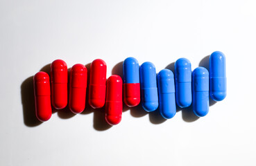 Red and Blue Pill Capsules on White Background with Strong Shadows © Anna Hoychuk