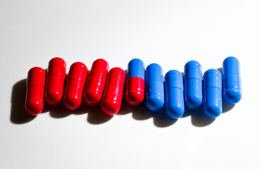 Red and Blue Pill Capsules on White Background with Strong Shadows © Anna Hoychuk