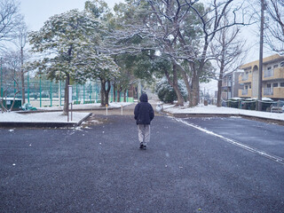 冬の朝の積雪の公園で散歩する子供の様子
