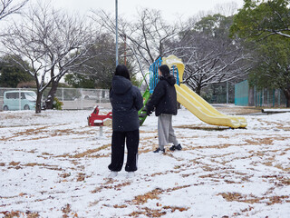 冬の朝の積雪の公園で楽しく雪合戦で遊んでいる子供姉妹の姿