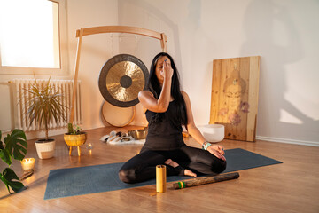 Young fit dark hair woman doing alternate nostril breathing, part of pranayama , fingers on third eye