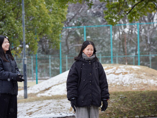 冬の朝の積雪の公園で楽しく雪合戦で遊んでいる子供姉妹の姿