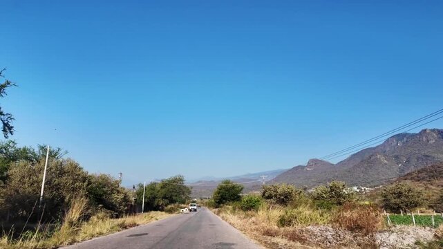 Manejando en paisaje rural mexicano, cielo azul.