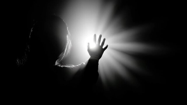 Misty backlight with dramatic light rays casting dark silhouette and shadow of hand fingers spread wide in eerie misty atmosphere