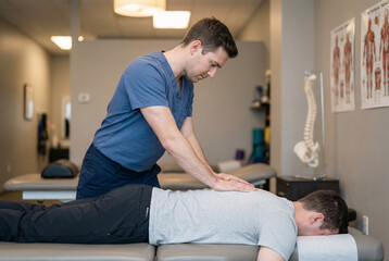 Professional physiotherapist performing back massage treatment on patient indoors, highlighting healthcare therapy, body recovery and physical wellness support.