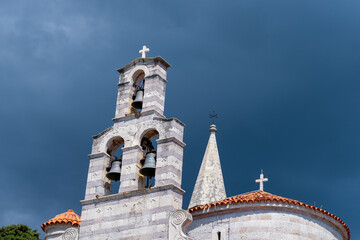 An impressive stone Orthodox bell tower rises beneath a stormy sky, adorned with crosses and architectural details. This impressive backdrop highlights the church historic character and elegance.