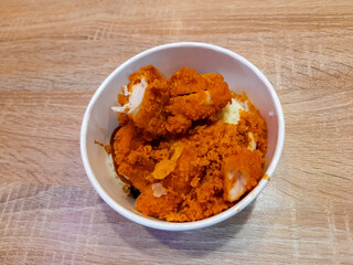 Rice bowl with white rice topped with crispy fried chicken pieces coated in orange seasoning. Popular fast food meal served in a bowl, simple and filling comfort food.