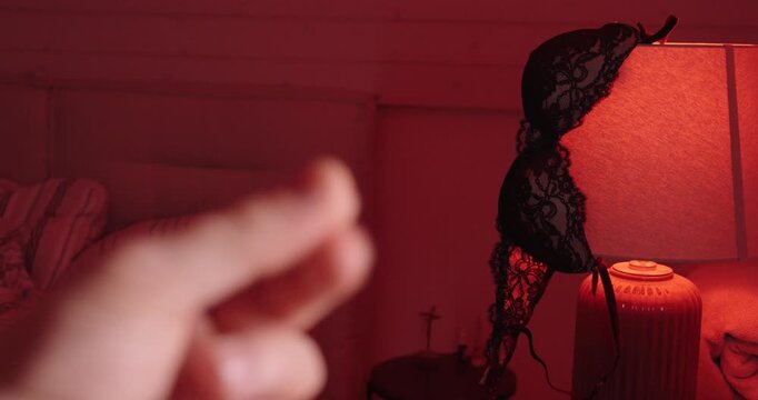 Close-up of a hand offering cash in a red-lit room with lingerie in the background, implying an adult-services transaction, secrecy, and moral tension