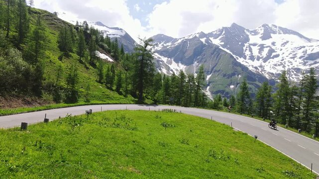 Mountain cyclists ride opposite directions on a winding alpine road in summer