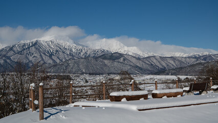 高台から望む街並みと冬の北アルプス