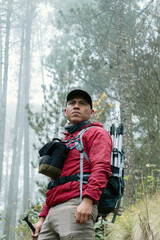 Male hiker with backpack trekking through foggy forest