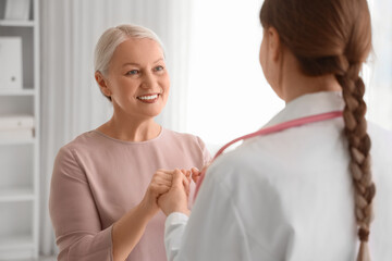 Obraz premium Mature woman with gynecologist holding hands in clinic. Menopause concept