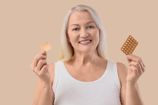 Mature woman with contraceptive patch and pills on beige background. Menopause concept