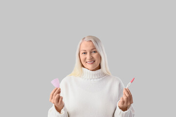 Mature woman with menstrual cup and pregnancy test on light background. Menopause concept