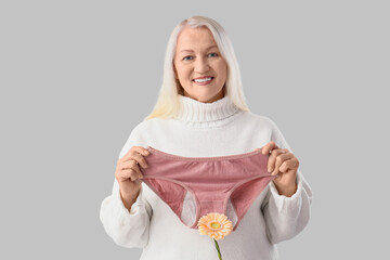 Mature woman with menstrual panties and flower on light background. Menopause concept