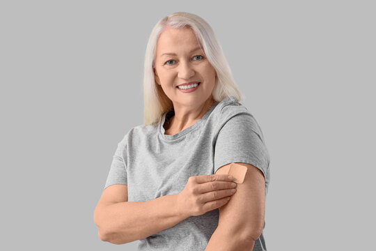 Mature woman applying contraceptive patch on light background. Menopause concept