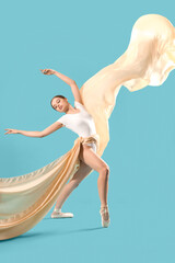 Fototapeta premium Young ballerina with fabric dancing on blue background