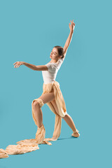 Obraz premium Young ballerina with fabric dancing on blue background
