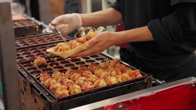 Chef picking up octopus takoyaki, a popular Japanese Osaka street food for tourists