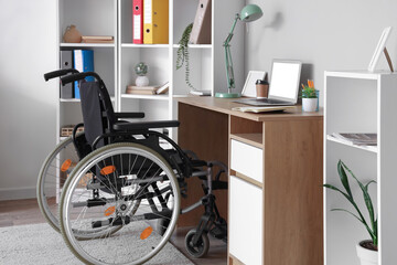 Interior of light office with shelf unit, workplace and wheelchair
