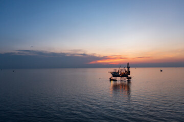 Aerial view of offshore jack up rig in a shipyard during sunset for oil and gas exploration and production.