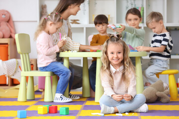 Cute little girl sculpting from plasticine in kindergarten