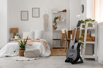 Interior of light bedroom with guitars, workplace and plants