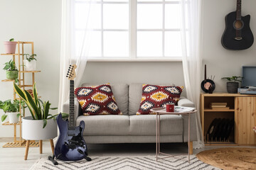 Interior of living room with sofa, guitars and plants