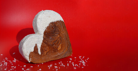 Heart shaped coconut flavor croissant on red background with copy space. Puff pastry new trendy sweet dessert bakery. Creamy dough experiment 