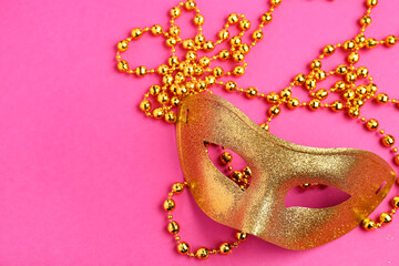 Shiny golden carnival mask with beads for Mardi Gras celebration on pink background © Pixel-Shot