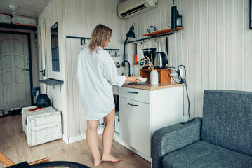 A young Caucasian woman with long brown hair stands in a cozy cabin kitchen. The space is bright and inviting, perfect for a vacation escape.