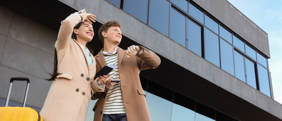 Obraz premium Young couple with passports looking at wristwatch near airport