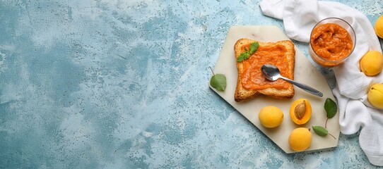 Naklejka premium Bowl of tasty apricot jam and slice of bread on blue grunge background with space for text