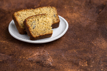 Slices of fresh baked banana bread on a white plate and  brown rustic background
