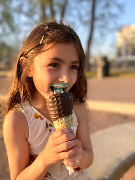Cute little girl with missing front teeth eating an ice cream cone on a sunny summer afternoon in a city
