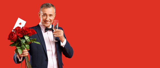 Happy mature man with bouquet of rose flowers, love letter and champagne on red background....
