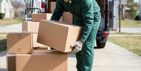 Delivery person unloads cardboard boxes from a van on a sunny day. Careful handling of packages shows commitment to efficient and safe delivery services.