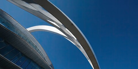 Modern architectural composition against a vibrant blue sky, featuring curved structures and glass facade
