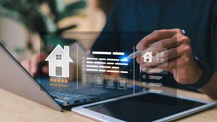 Person using digital tablet and laptop with virtual real estate interface, featuring house icon, rating stars, documents, and property checklist. Concept of smart property management.