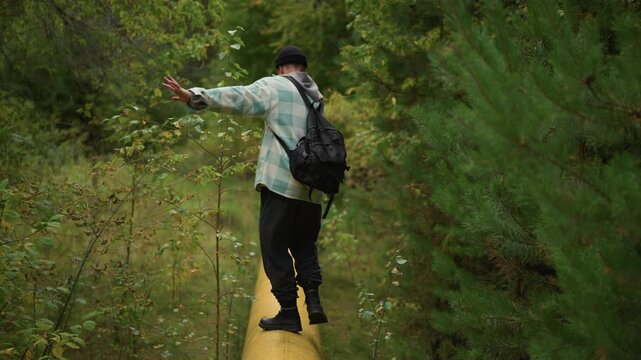 narrow boardwalk hiker crossing dense thicket overhead perspective of traveler balancing arms while navigating wooden path through tight woodland corridor lush green foliage close branches calm pace