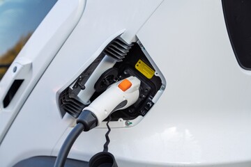 An electric vehicle charging, symbolizing the transition to sustainable mobility. This image...