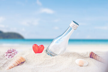 bottle on sand beach over blurred tropical blue sea and clear blue sky.