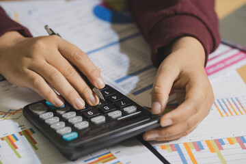 Accountant working Financial investment on calculator and laptop with tablet on withe desk.