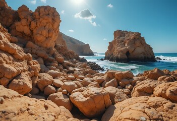 Sunlit rugged coastal boulder field with azure sea and distant rocky headlands