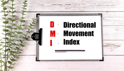 Directional movement index abbreviation written on clipboard with silver pen and green plant on wooden background
