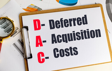 Deferred acquisition costs acronym on clipboard with financial charts and magnifying glass