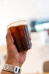 Closeup cold brew iced americano coffee with ice cubes no straw side view on man hand