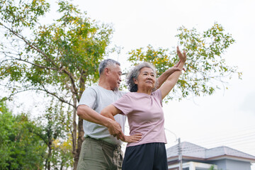 Asian senior man and woman exercise together in a park, showing elderly couple enjoying fitness activity, healthy lifestyle and relationship outdoors.